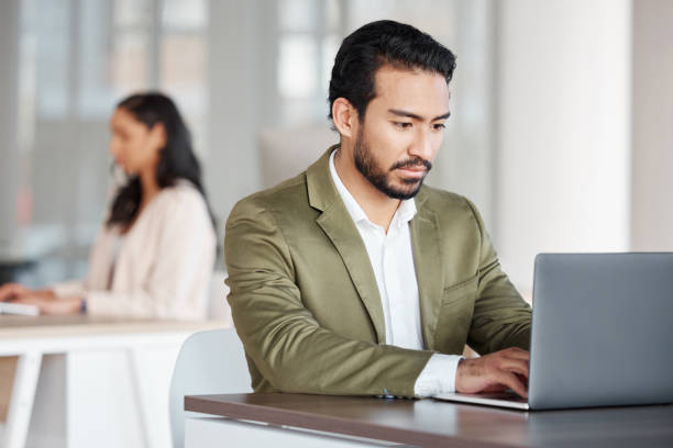 istock Focused business man typing on laptop at office desk, planning information and digital tech project. Male employee working on computer for data update, website strategy and research for online report 1573797101