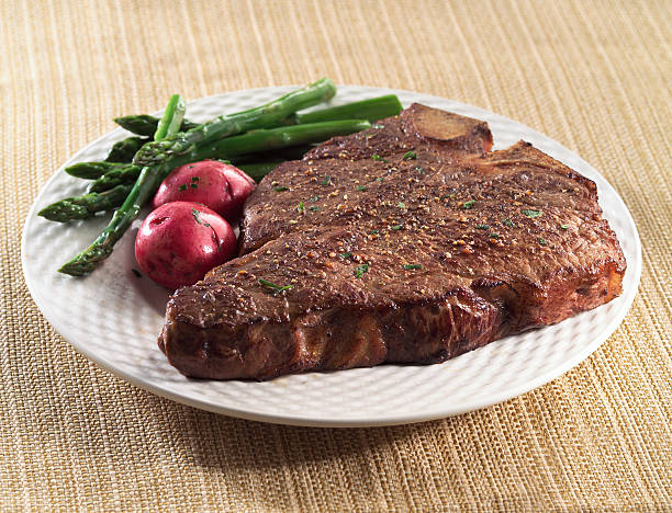 Porterhouse Porterhouse steak on white plate with red skin potatoes and asparagus, shot with shallow focus. porterhouse steak stock pictures, royalty-free photos & images