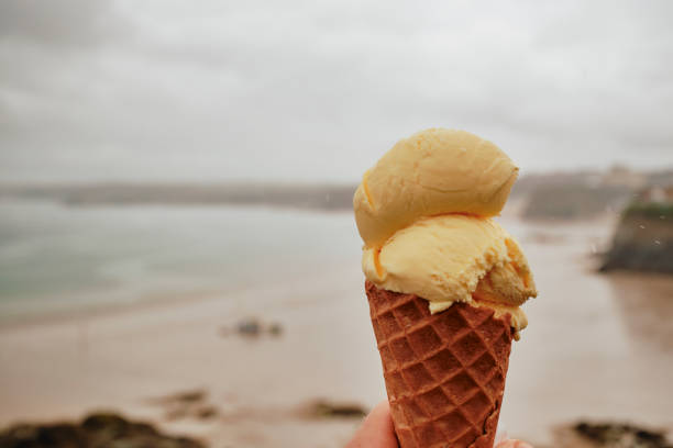 POV of a hand holding a Vanilla Ice cream above Newquay Towan Beach on a rainy June day. stock photo