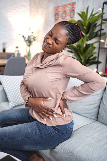 istock Black woman suffering with back pain while sitting at home 1573802053