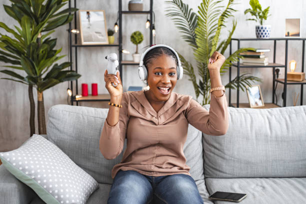 istock Black woman feeling excited about winning in a video game 1573802597