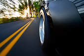 Ground view of car tire speeding along country road sunset