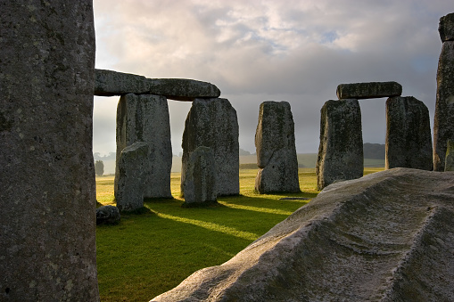 The sun rises, shedding it's rays through the massive hand carved stones at Stonehenge built on the Salisbury plains thousands of years ago.