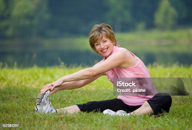 Mujer Sonriente De Estar Y Sextiende Más De Piernas En El Parque Foto de stock y más banco de imágenes de 60-64 años