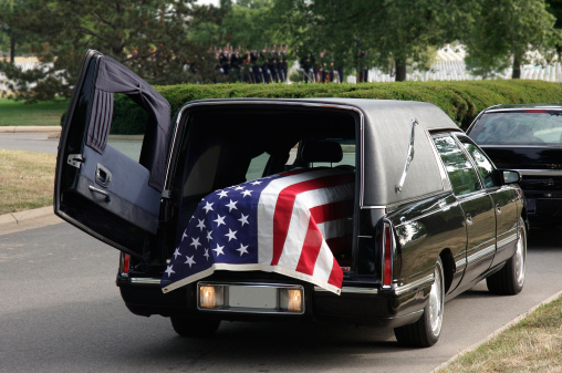 Closeup of coffin with flowers at outdoor funeral ceremony for army veteran, copy space