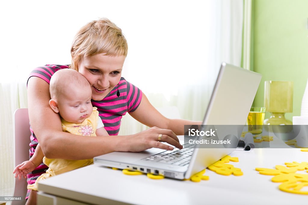 Mama z dzieckiem, korzystający z laptopa - Zbiór zdjęć royalty-free (Biurko)