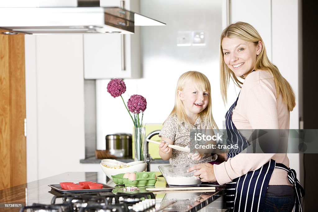 Feliz madre ayudando a su hija cocinar pasteles en la cocina - Foto de stock de 2-3 años libre de derechos
