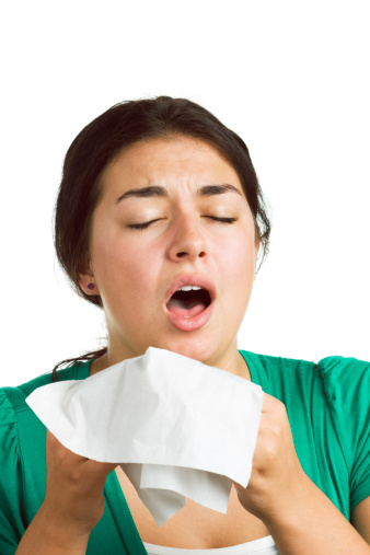 A young woman sneezing and coughing from cold and flu, allergy, virus, or hay fever.