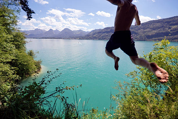 Live a Little! Photo sequence of a young man leaping off a cliff into a blue Alpine lake below on a hot summer day. Slight motion blur on young man as he flies through the air. cliff jumping stock pictures, royalty-free photos & images