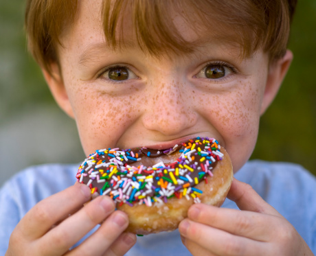 Boy eating, freckle face child holding unhealthy chocolate donut. (SEE LIGHTBOXES BELOW for more photos of this model & breakfast foods...)