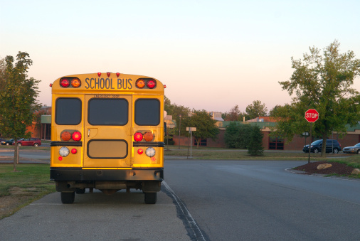Close-up view of a yellow school bus sign and lights with blue sky background.