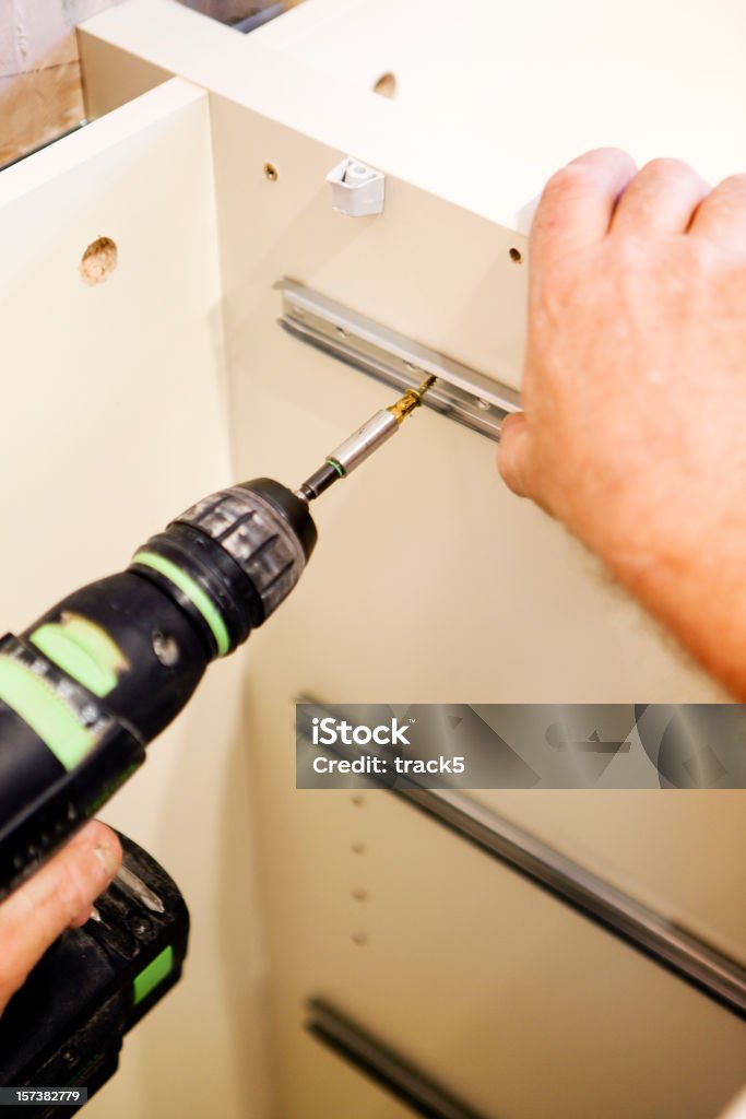 Kitchen fitters: fitting drawer runners using an electric screwdriver  Cabinet Stock Photo