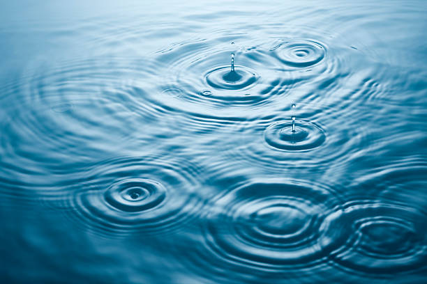 Wavy ripples Multiple drips and ripples on bright blue calm water soft focus stock pictures, royalty-free photos & images