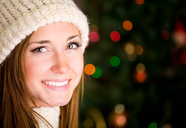 A close-up of a young woman in front of a Christmas tree.