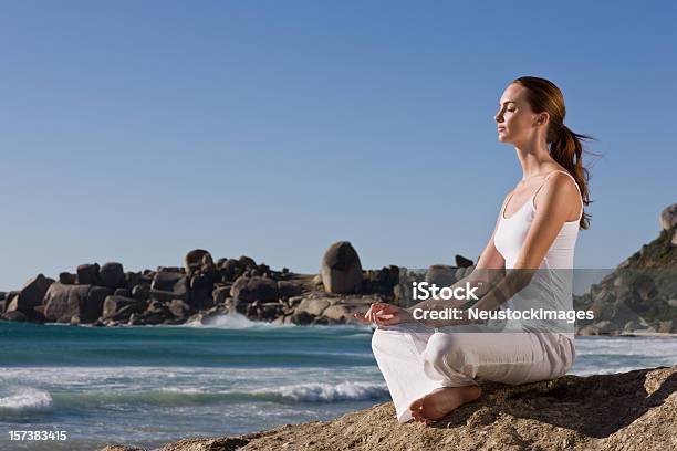 Junge Frau Meditieren Auf Felsen Am Meer Stockfoto und mehr Bilder von 20-24 Jahre - 20-24 Jahre, Attraktive Frau, Augen geschlossen