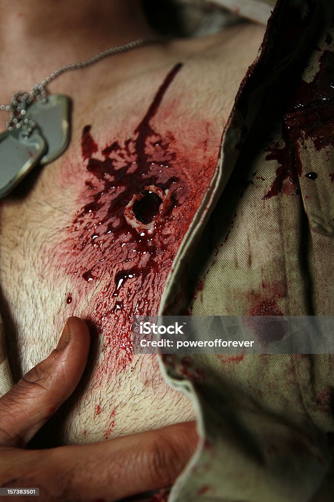 Military hombre con máquinas de disparo de pistola de herida en el lado izquierdo del pecho - Foto de stock de Agujero de bala libre de derechos