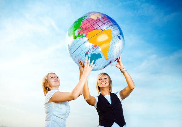 A young Asian woman, an airplane passenger, sits at her seat holding a world globe. Her travel essentials include a boarding pass, Earth day, Sustainable Fuel and Green energy, Save the world.