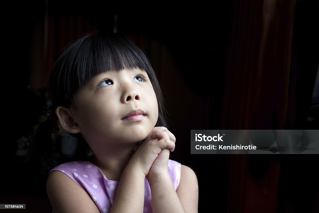 Make a wish Little child is making a wish isolated in dark background Asian and Indian Ethnicities Stock Photo