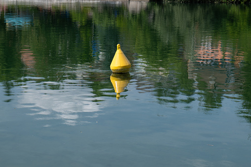 Yellow floating buoy on a river in Europe. Sunny summer day, no people.