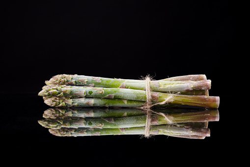 Fresh green asparagus in eco mesh bag on black slate background. Top view copy space.