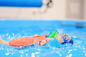 Little boy with glasses and inflatable armbands in swimming pool.