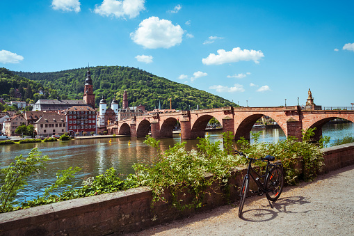 view on the  historic Karl Theodor bridge in Heidelberg with cityscape and town gate in the background, bicycle in the foreground