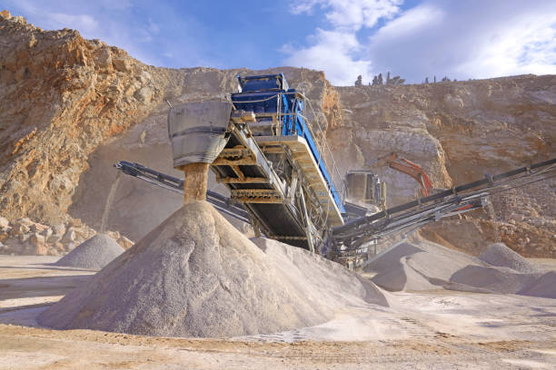 The quarry, stone crushing and production of building materials, sand and gravel Stone crushing machine at open pit mining and processing plant for crushed stone. Piles of gravel stone and conveyor belts on the side of the road. Concepts of industry and building materials, sand and gravel mining conveyor belt stock pictures, royalty-free photos & images