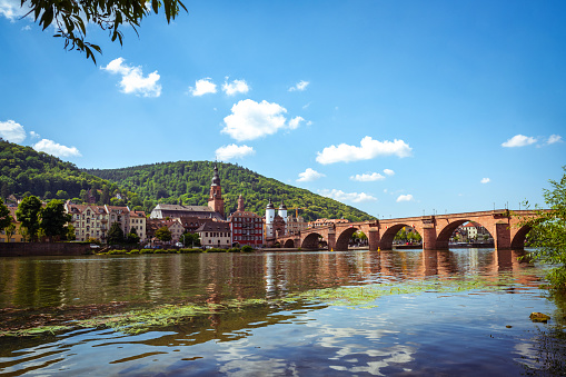 view from Neckar river on the  historic Karl Theodor bridge in Heidelberg with cityscape and town gate in the background