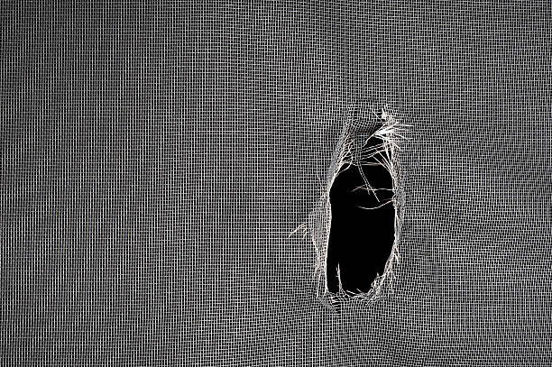 Torn window screen Window screen torn with a big hole against a black background. torn fabric stock pictures, royalty-free photos & images