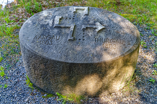 Stone with engraving of Cantons Aargau and Thurgau at hiking trail Swiss path on a cloudy spring day. Photo taken May 22nd 2023, Sisikon, Switzerland.
