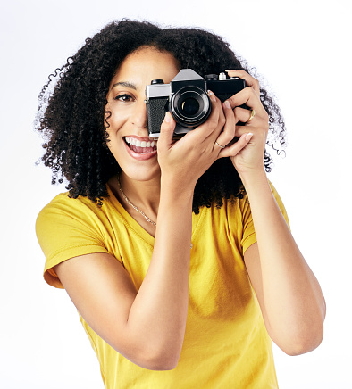 Photography, camera and happy woman photographer and happy as a creative isolated in a studio white background. Portrait, photoshoot and artistic person with a hobby and takes picture of memory