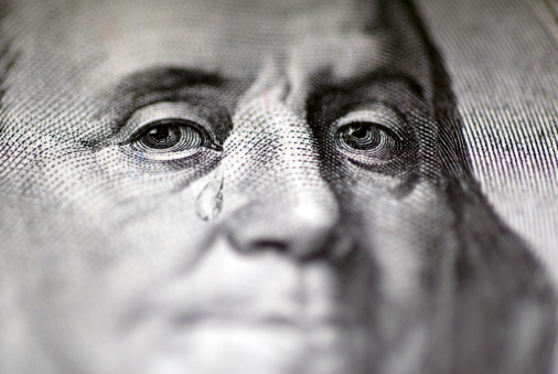 Tear falling from face on US dollar bill, close-up