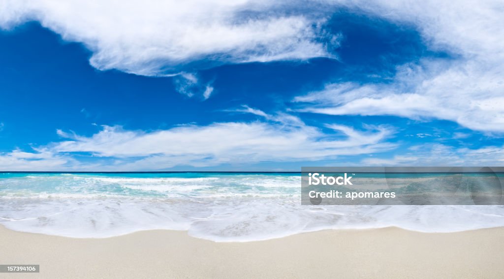 Tropical Beach and cloudy deep blue sky Cloudscape and gentle waves of the turquoise waters in a  Tropical island white sand beach. Relaxing, travel and leisure related images for vacations in the Caribbean. Image taken at Morrocoy National Park, Venezuela. Morrocoy is a coastline and a group of small islands and cays located at Falcon State in Venezuela. A very popular destination for leisure, diving, kite surfing and all kind of water activities. Morrocoy and the beauty of the turquoise coastal beaches of Venezuela are almost indistinguishable from those of the Bahamas, Fiji, Bora Bora, French Polynesia, Malau, Hawaii, Cancun, Costa Rica, Florida, Maldives, Cuba, Puerto Rico, Honduras, or other tropical areas. Beach Stock Photo