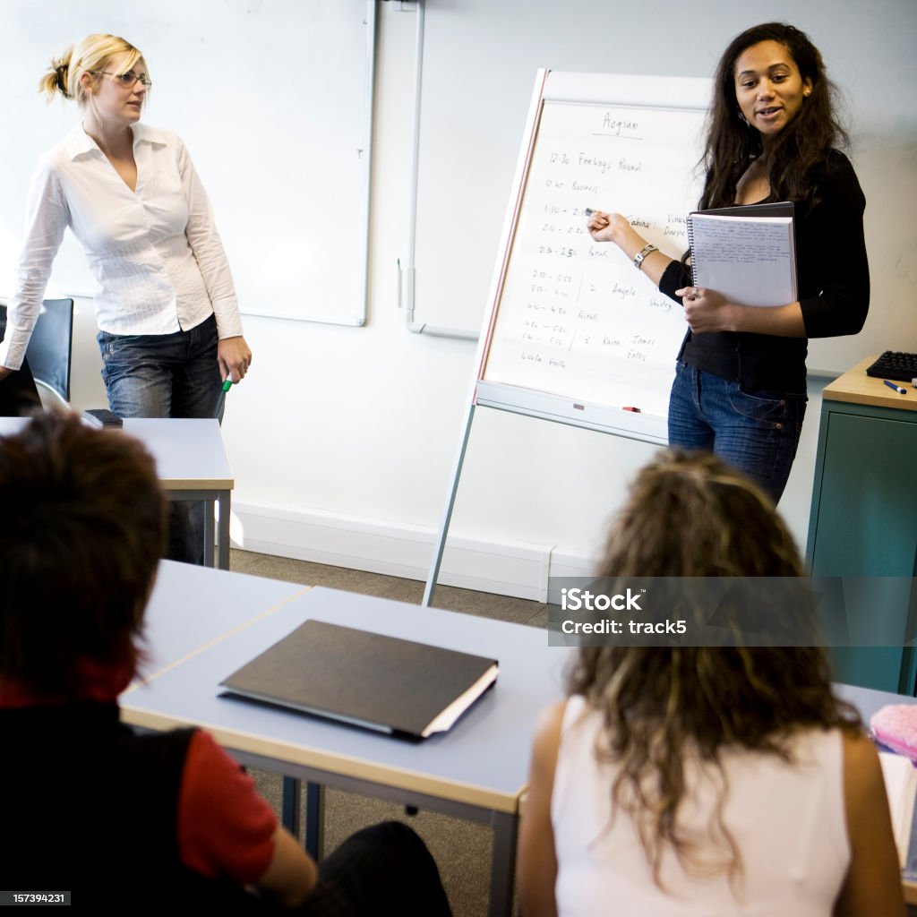 Adolescente estudante abordar a classe sob supervisão do Professor - Foto de stock de Sala de aula royalty-free