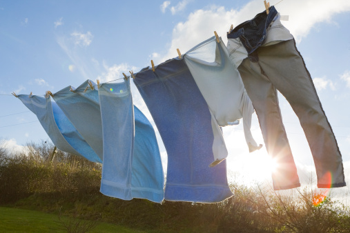 White sheets hanging up on a washing line drying outside.