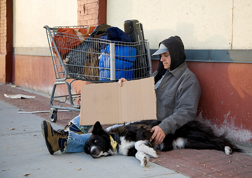 A homeless man sitting on a sidewalk.