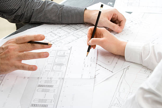 istock Two pairs of hands working on architectural drawings 157395184