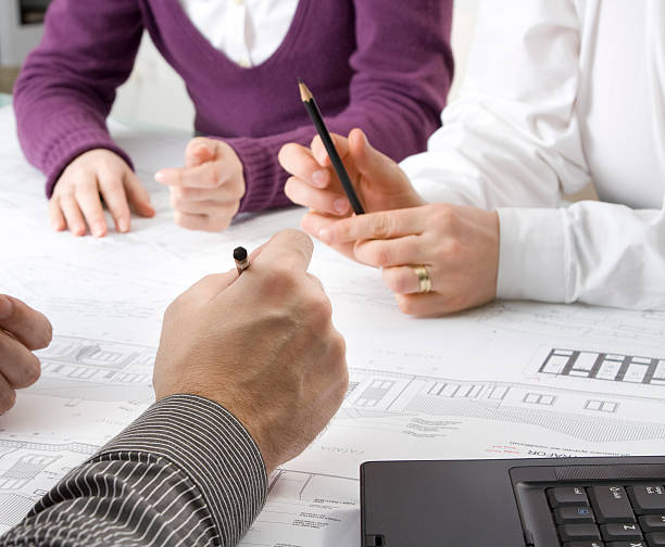 istock One woman and two men at a desk looking over plans 157395188