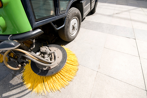 The machine washes and vacuums the sidewalks in the park.
