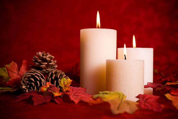 Christmas decorations with pine cones and burning candle on black wood