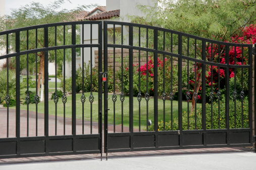 Large decorative Wrought Iron gates on condo complex. Red Lock and Red Flowers.