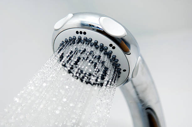 A modern chrome shower head in full flow. Focus on jets at top of head. Individual droplets of water visible.