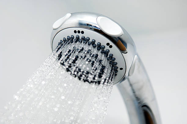 A close-up of a silver chrome shower head spouting water stock photo