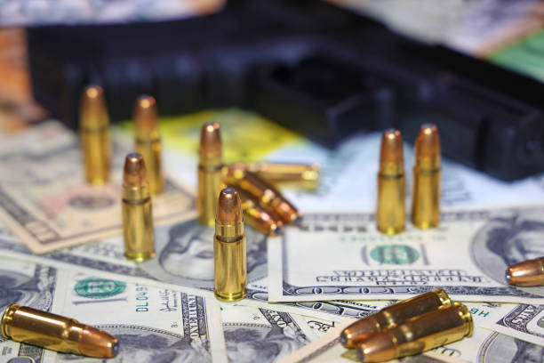 pistola y balas en el fondo de los billetes de dólar y euros - gun currency crime mafia fotografías e imágenes de stock