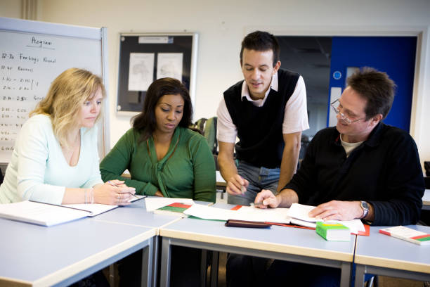 istock adult education: a teacher helping a group of mature students 157395895