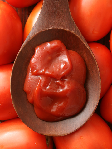 Top view of wooden spoon full of ketchup sauce