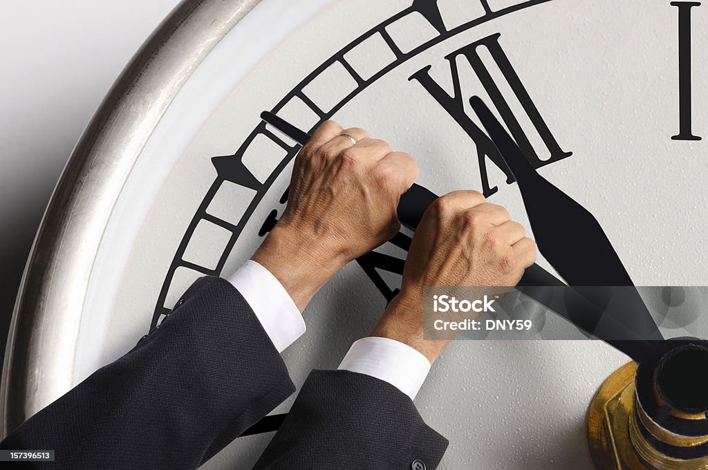 Businessman trying to hold back the hands on a clock A conceptual look at trying to stop time from progressing. Holding Back The Hands Of Time Stock Photo