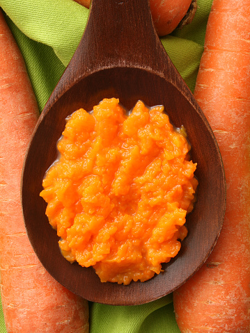 Top view of wooden spoon full of carrot puree