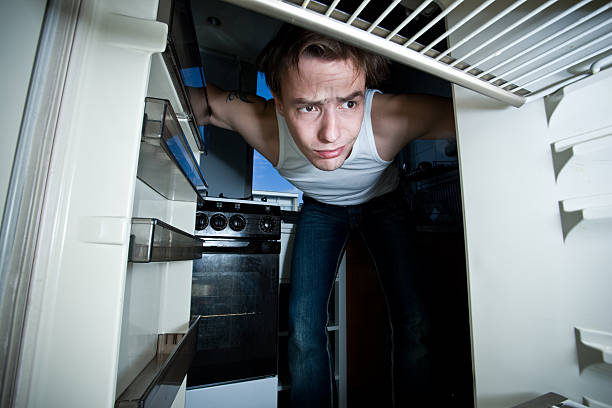 istock Young man leaning in to look at empty fridge 157397140
