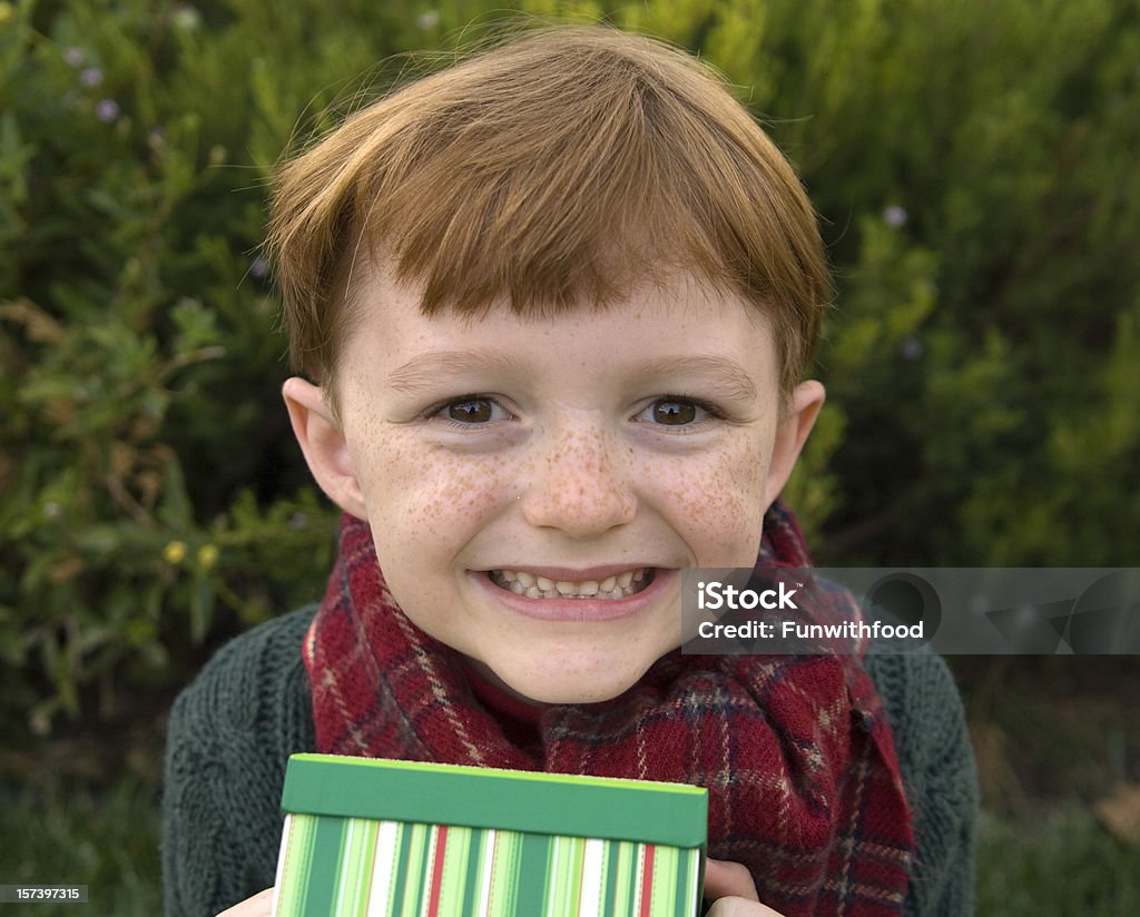 Мальчик, давая Рождественский подарок, ребенок улыбается держит праздник Подарочная коробка - Стоковые фото Веснушка роялти-фри